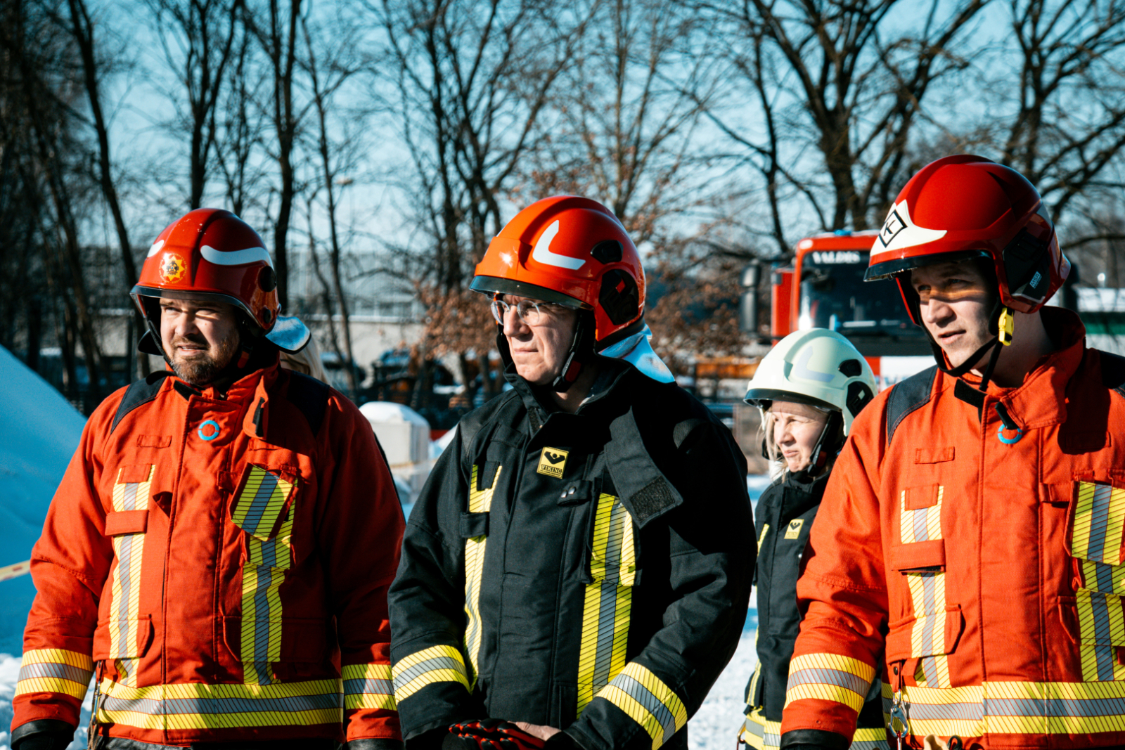Valsts prezidents Edgars Rinkēvičs stāv ārā sniegotā teritorijā ar diviem koledžas pārstāvjiem. Fonā ugunsdzesības transportlīdzeklis un koki.